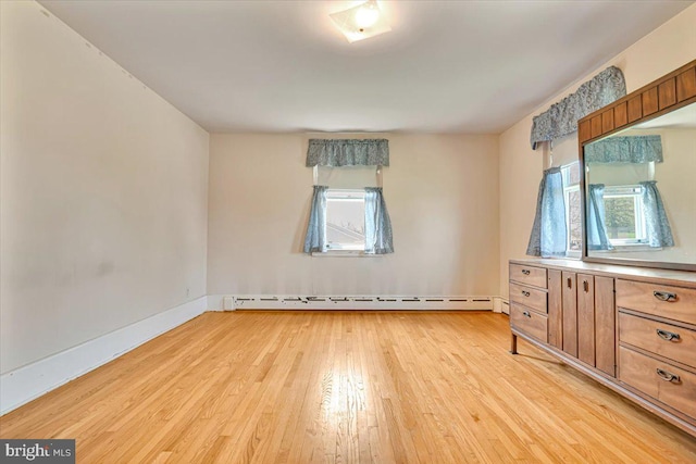 empty room featuring light wood-style floors, baseboards, and a baseboard heating unit