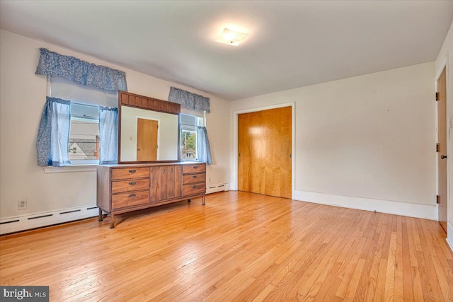 unfurnished bedroom with baseboards, baseboard heating, and hardwood / wood-style floors