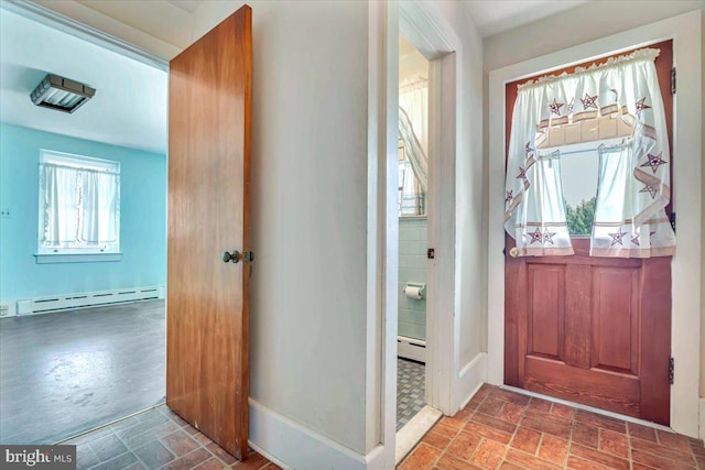 entrance foyer with baseboards, a baseboard heating unit, and brick floor