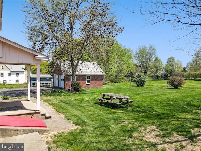 view of yard with a garage, fence, and an outbuilding