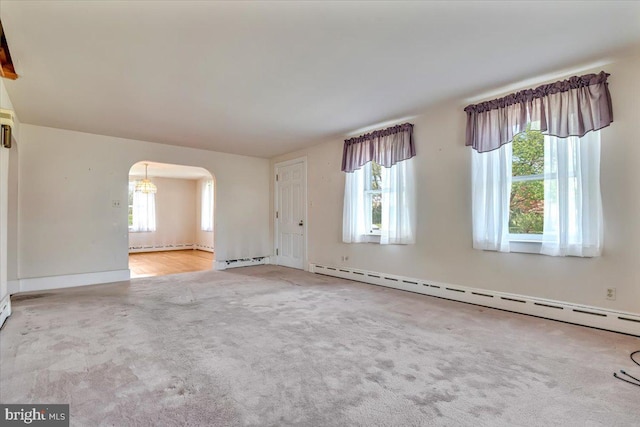 interior space featuring arched walkways, carpet, a baseboard heating unit, and a notable chandelier