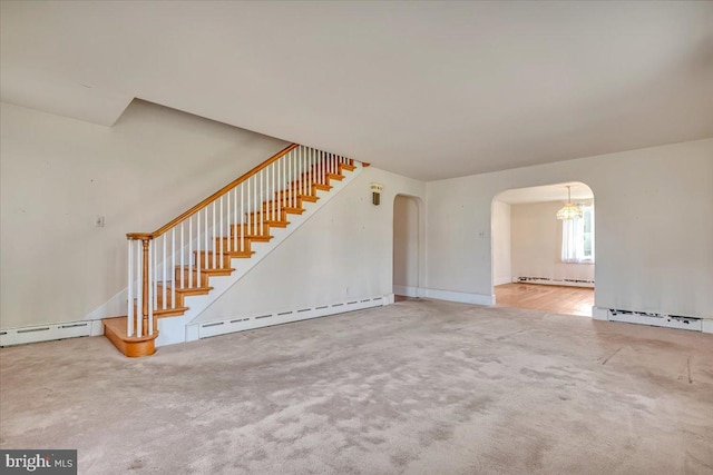 unfurnished living room featuring stairs, arched walkways, and a baseboard heating unit