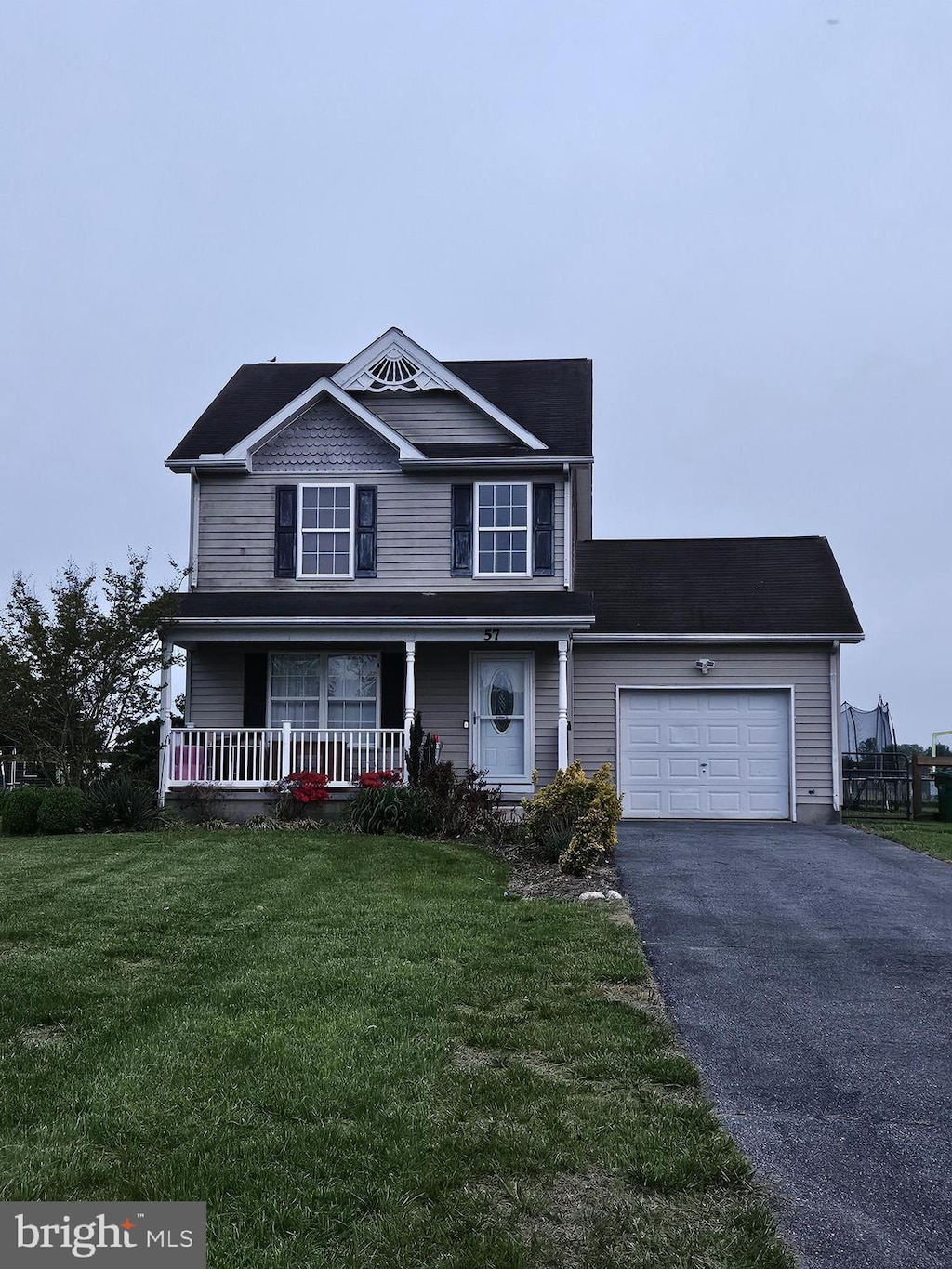 view of front of house featuring a garage, aphalt driveway, covered porch, and a front yard