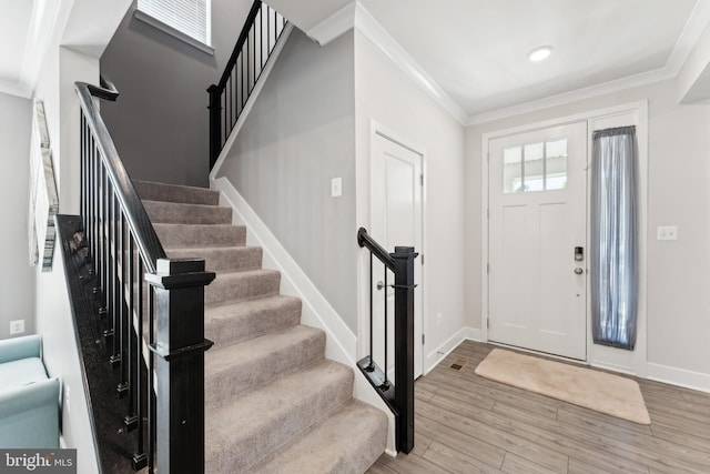 entrance foyer with stairs, baseboards, ornamental molding, and wood finished floors