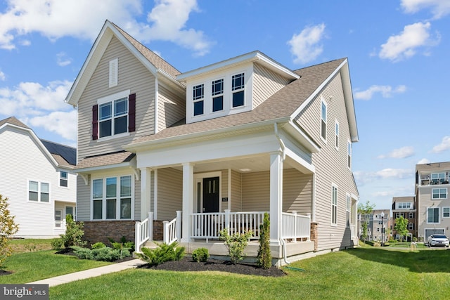 view of front of property with covered porch, a shingled roof, and a front yard