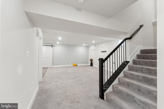 finished basement with a barn door, carpet, stairs, recessed lighting, and baseboards