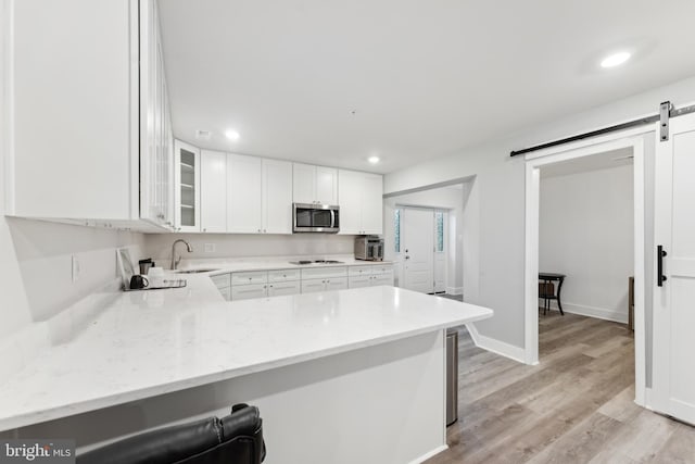 kitchen with light stone counters, stainless steel microwave, stovetop, and a barn door