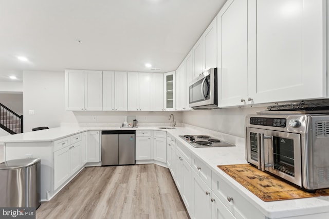 kitchen featuring white cabinets, appliances with stainless steel finishes, light countertops, a peninsula, and a toaster