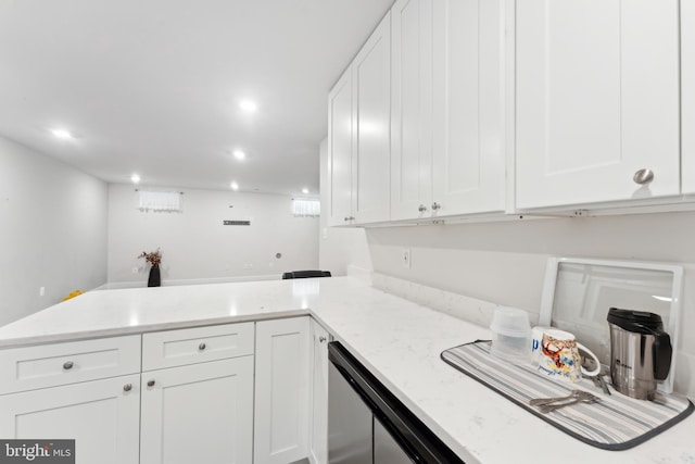 kitchen with light stone counters, a peninsula, and white cabinetry