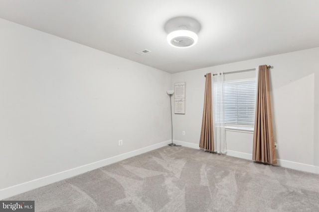 carpeted empty room featuring baseboards and visible vents