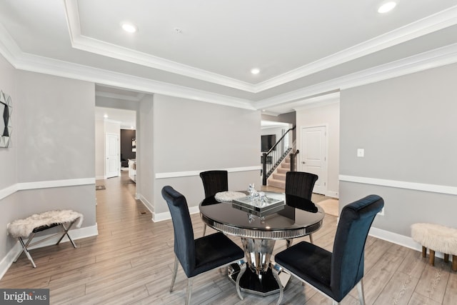 dining space with light wood-type flooring, stairs, baseboards, and a tray ceiling