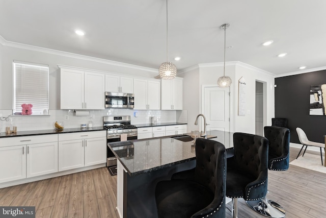 kitchen with backsplash, crown molding, a sink, light wood-style floors, and stainless steel appliances