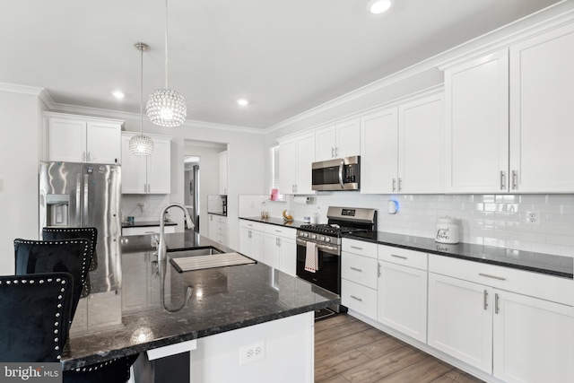 kitchen featuring crown molding, appliances with stainless steel finishes, a sink, white cabinetry, and tasteful backsplash