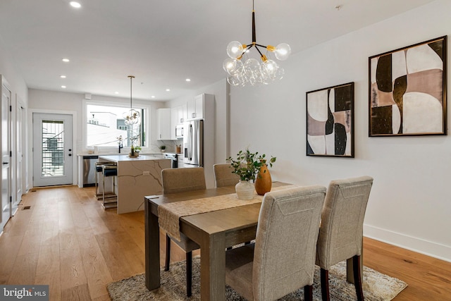 dining space featuring recessed lighting, baseboards, a chandelier, and light wood-style flooring