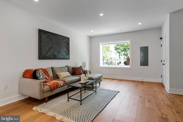 living area featuring recessed lighting, baseboards, light wood-type flooring, and electric panel