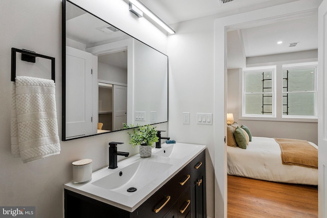 full bathroom with double vanity, visible vents, a sink, and wood finished floors