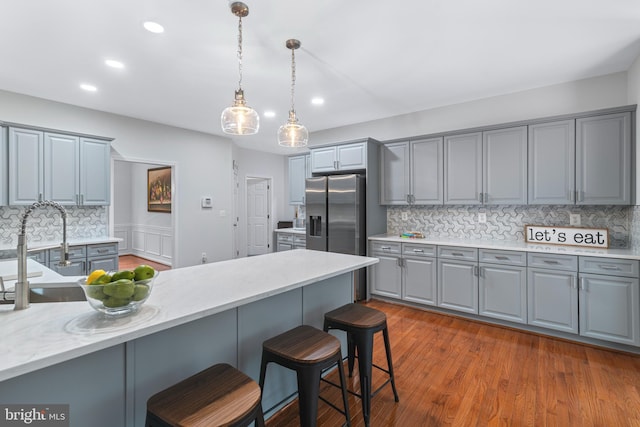 13647 Van Doren Rd, Manassas, VA 20112 - kitchen with gray cabinetry, stainless steel fridge, a kitchen bar, decorative backsplash, and recessed lighting