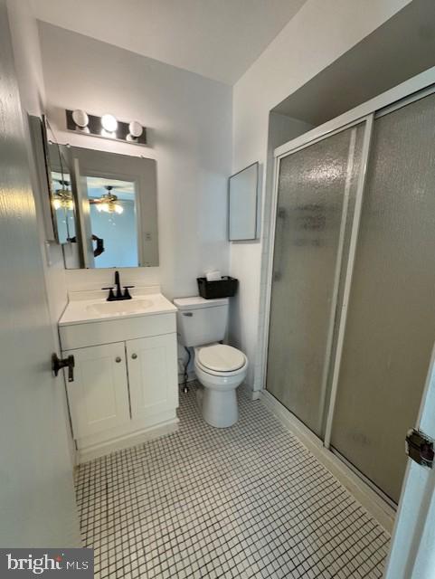 bathroom featuring vanity, a ceiling fan, a stall shower, and toilet