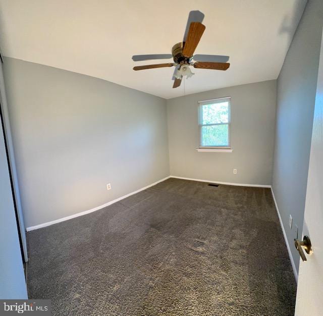 unfurnished room with baseboards, a ceiling fan, and dark colored carpet