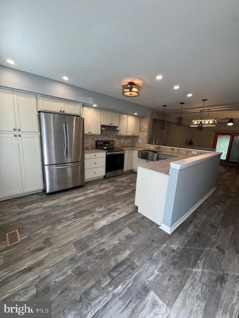 kitchen with pendant lighting, recessed lighting, under cabinet range hood, backsplash, and stainless steel appliances