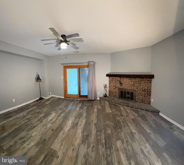 unfurnished living room with a ceiling fan, baseboards, wood finished floors, and a fireplace