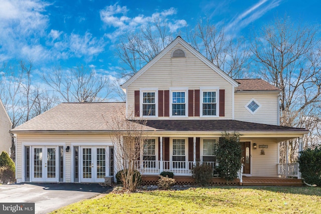 traditional-style home featuring french doors, a front lawn, covered porch, and roof with shingles