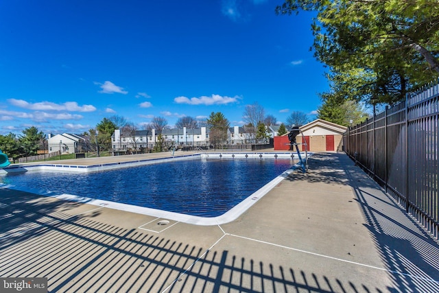 community pool featuring fence, a water slide, and a residential view