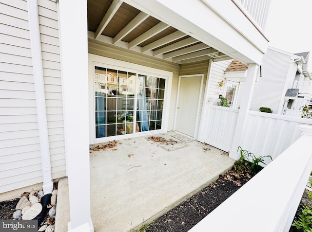 view of exterior entry with a patio area and fence