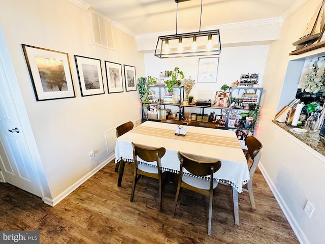 dining room featuring visible vents, ornamental molding, baseboards, and wood finished floors