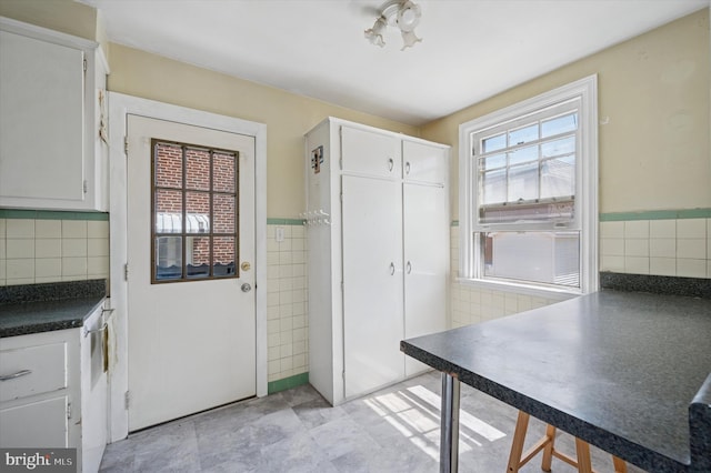 interior space with white cabinets, dark countertops, and tile walls