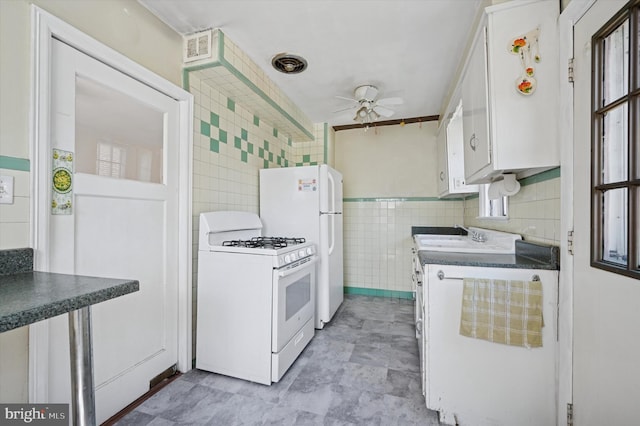 kitchen featuring ceiling fan, a sink, white appliances, white cabinetry, and tile walls
