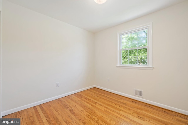 unfurnished room featuring baseboards, wood finished floors, and visible vents