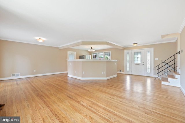 unfurnished living room featuring visible vents, stairway, baseboards, light wood-style floors, and ornamental molding