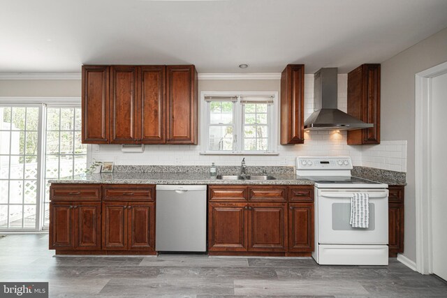 kitchen with wall chimney range hood, crown molding, dishwasher, a sink, and electric stove
