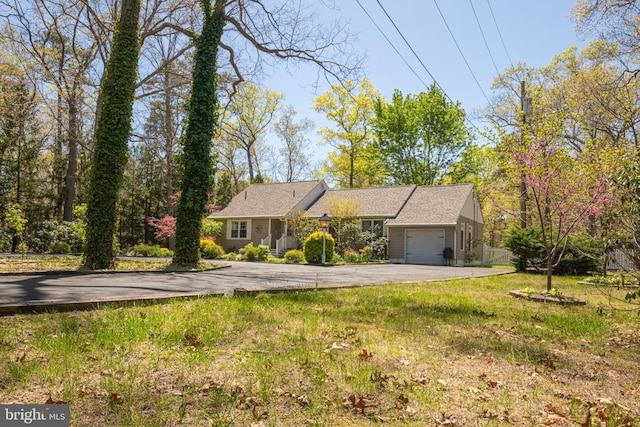 ranch-style house with a garage, a front yard, and aphalt driveway