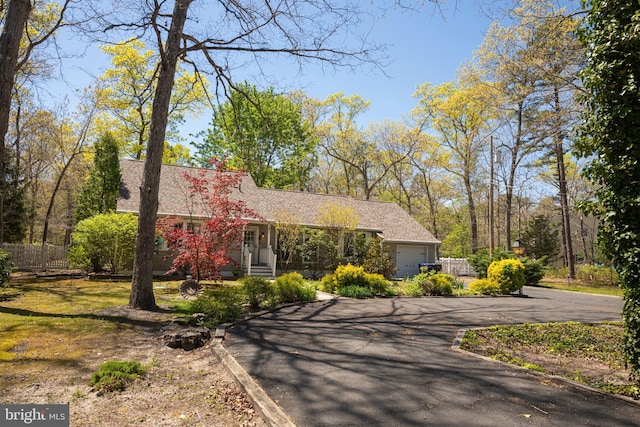 view of front of property featuring a garage, aphalt driveway, fence, roof with shingles, and entry steps