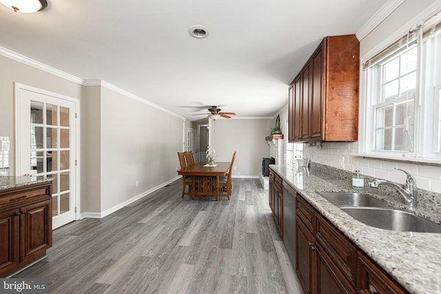 kitchen with ceiling fan, crown molding, wood finished floors, a sink, and baseboards