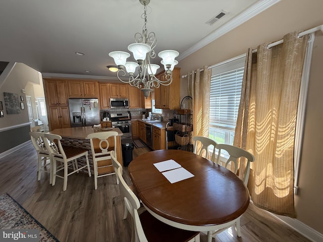 dining area featuring an inviting chandelier, a wealth of natural light, ornamental molding, and visible vents