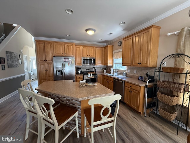 kitchen featuring appliances with stainless steel finishes, decorative backsplash, a center island, and wood finished floors