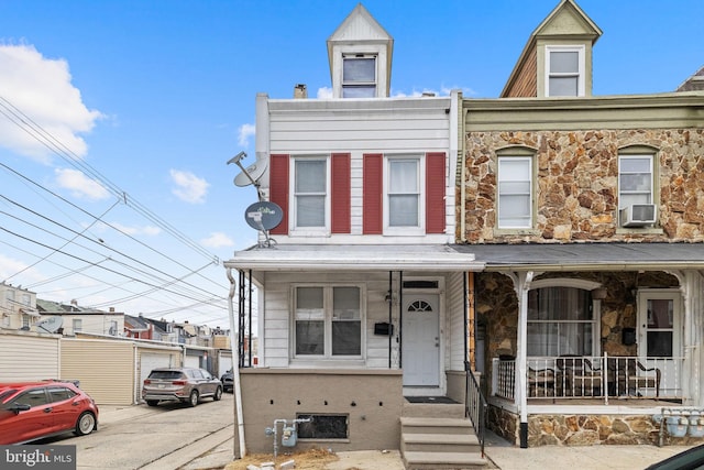 townhome / multi-family property with a porch and stone siding