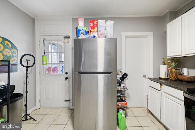 kitchen with freestanding refrigerator, white cabinetry, light tile patterned flooring, and dark countertops