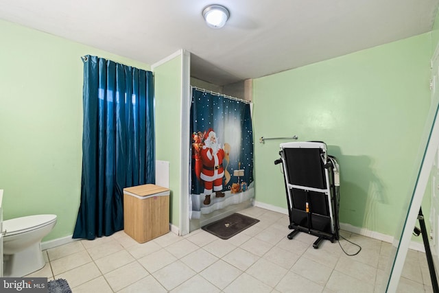 bathroom featuring baseboards, tile patterned flooring, and toilet