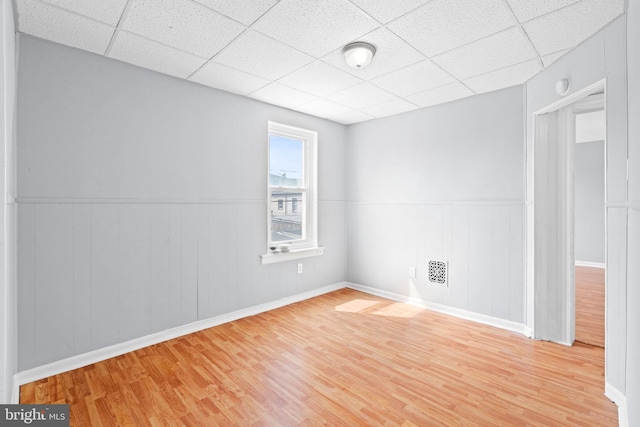 empty room featuring wood finished floors and a paneled ceiling