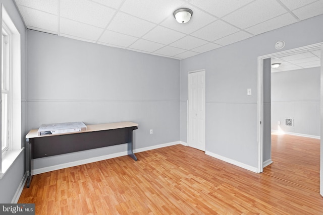 unfurnished bedroom featuring a closet, a drop ceiling, and light wood-type flooring