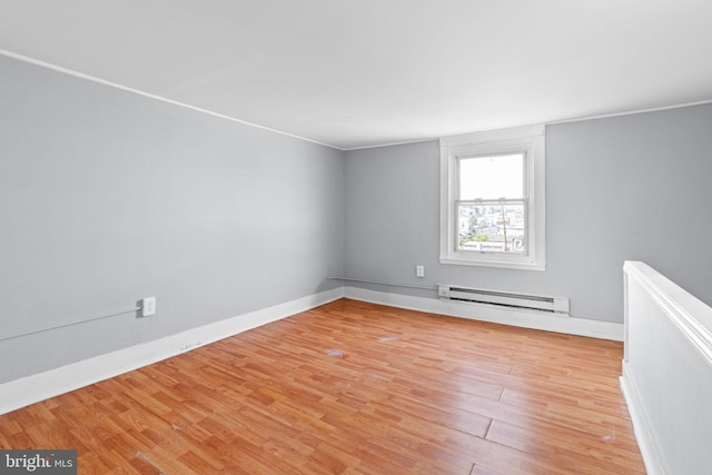 empty room with light wood-style floors, baseboards, and baseboard heating