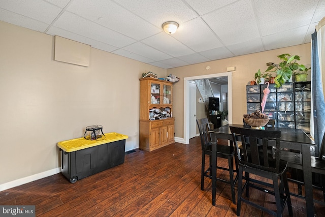 dining area featuring baseboards, dark wood finished floors, and a paneled ceiling