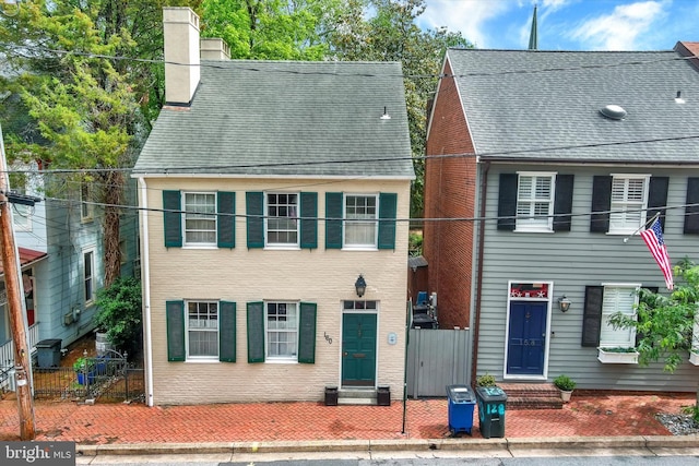 view of front facade featuring entry steps, fence, and a chimney