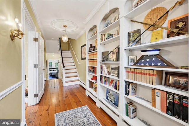 hall featuring ornamental molding, wood-type flooring, and stairway