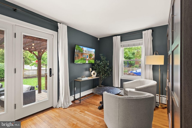 sitting room with light wood-type flooring, baseboard heating, and baseboards