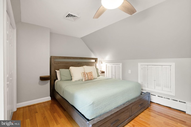bedroom featuring vaulted ceiling, light wood-type flooring, baseboards, a ceiling fan, and a baseboard heating unit